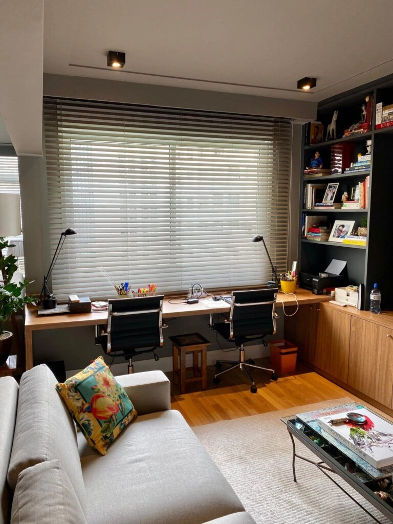 Persiana horizontal de madeira em home office moderno com mesa dupla e prateleiras organizadas.