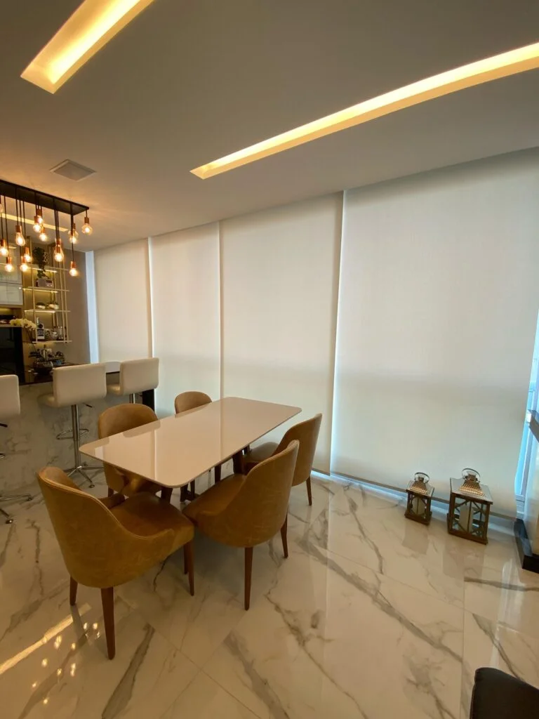 Sala de jantar moderna com persiana rolô sob medida, oferecendo conforto visual e sofisticação. Projeto Casa Chic Decor.